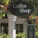 A vibrant green coffee shop sign featuring vinyl lettering, showcasing the name or logo of the café with eye-catching appeal.